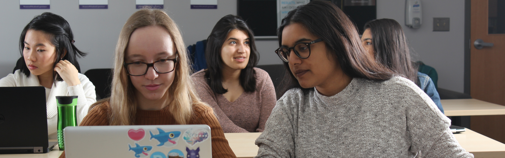 two students looking at a laptop together in a classroom