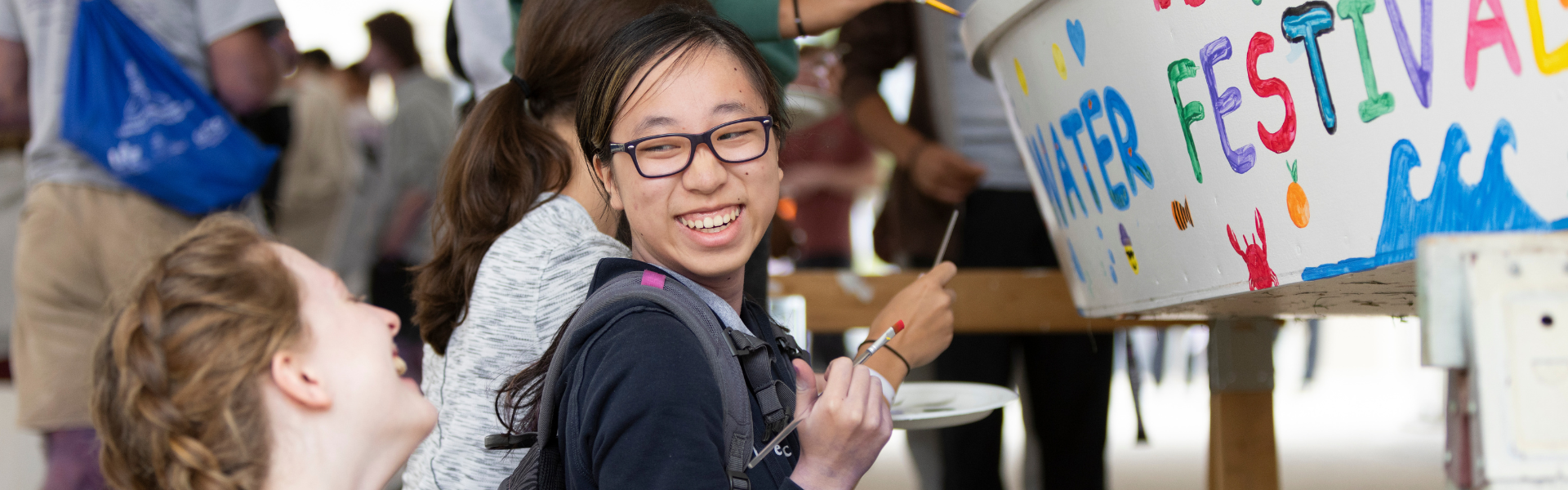 A photo of a student laughing while painting.