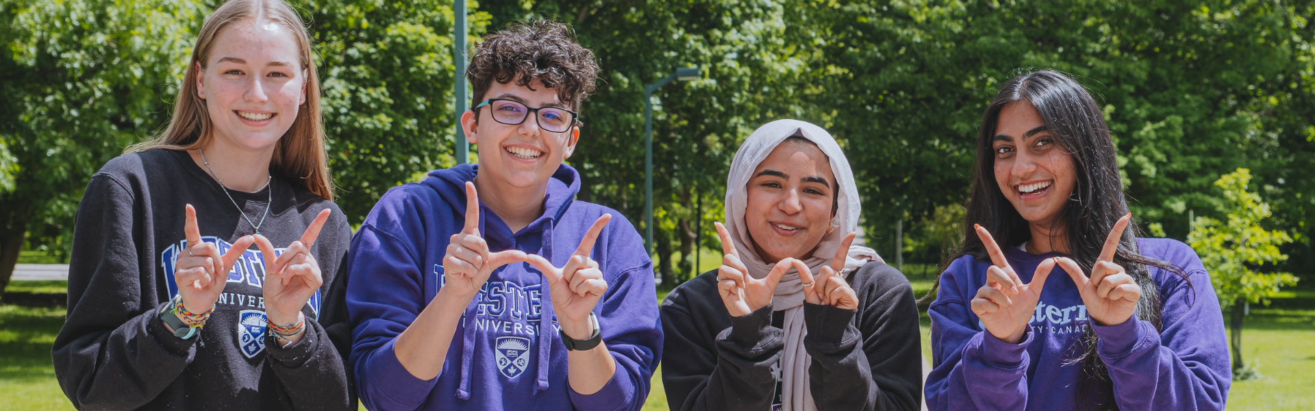 A photo of students smiling making a Western "w" with their hands