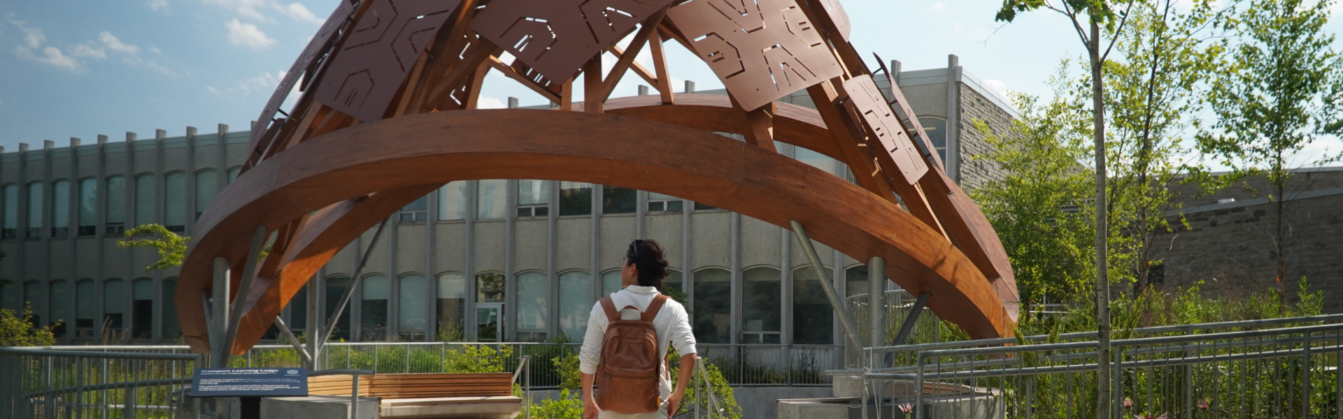 A photo of a student in front of the wampum learning lodge.